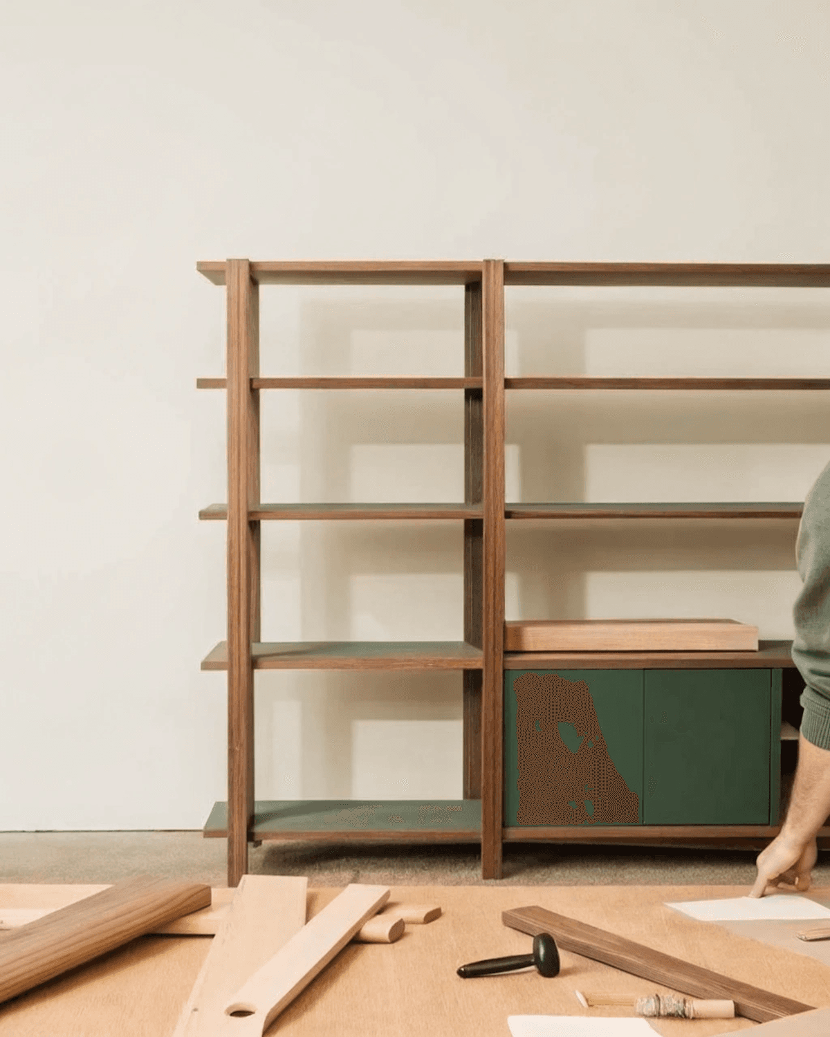 A wooden shelving unit holding tools and timber against a pale wall