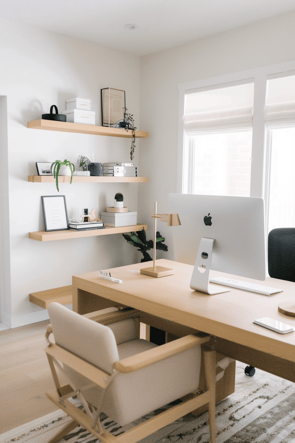 A tidy home office with a wooden desk, floating shelves and daylight from a nearby window